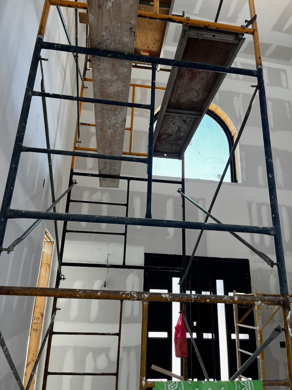Scaffolding inside a building, near a window and door. Boards are in place for working.