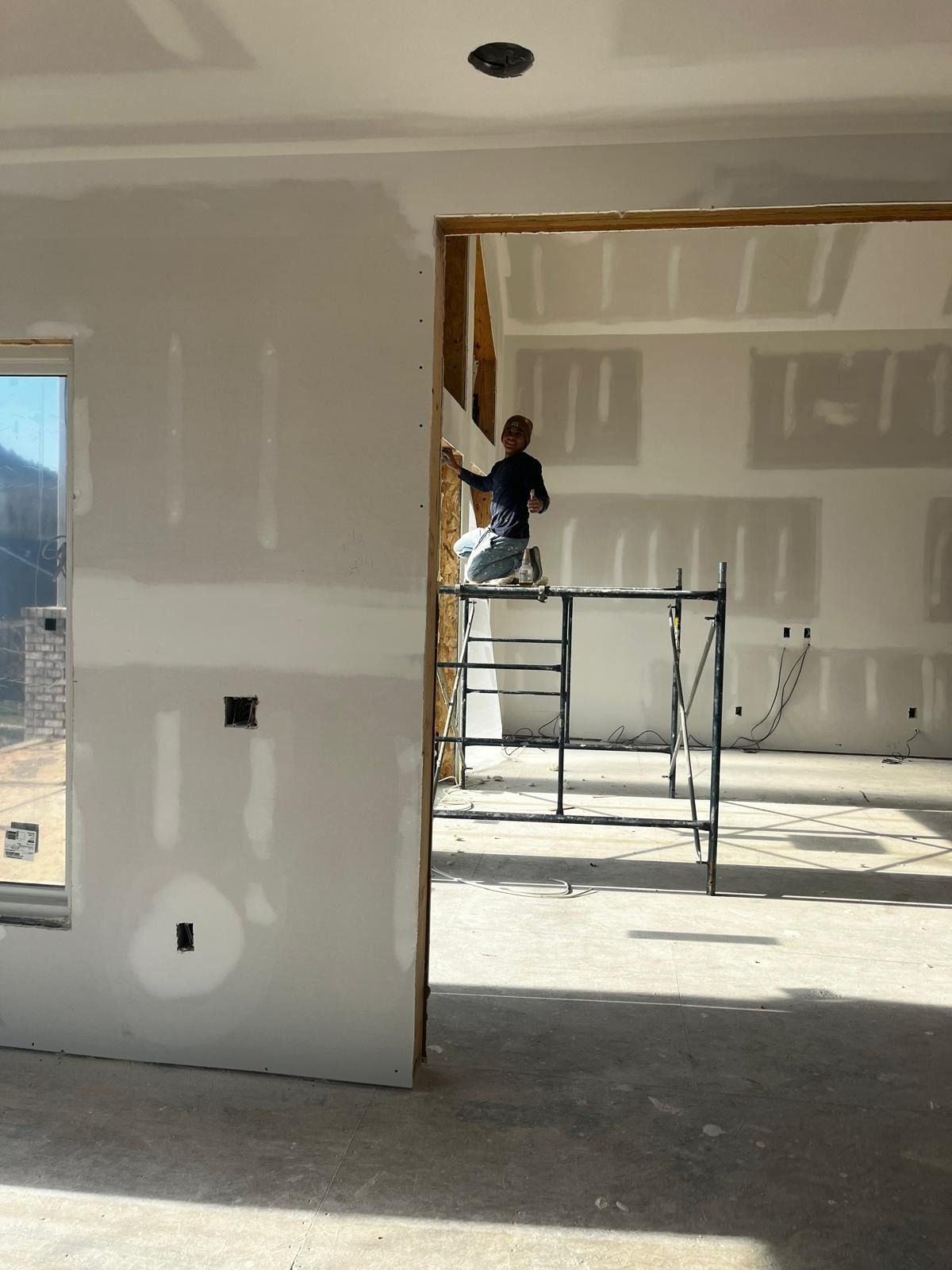 Man on scaffold taping drywall in new home construction.