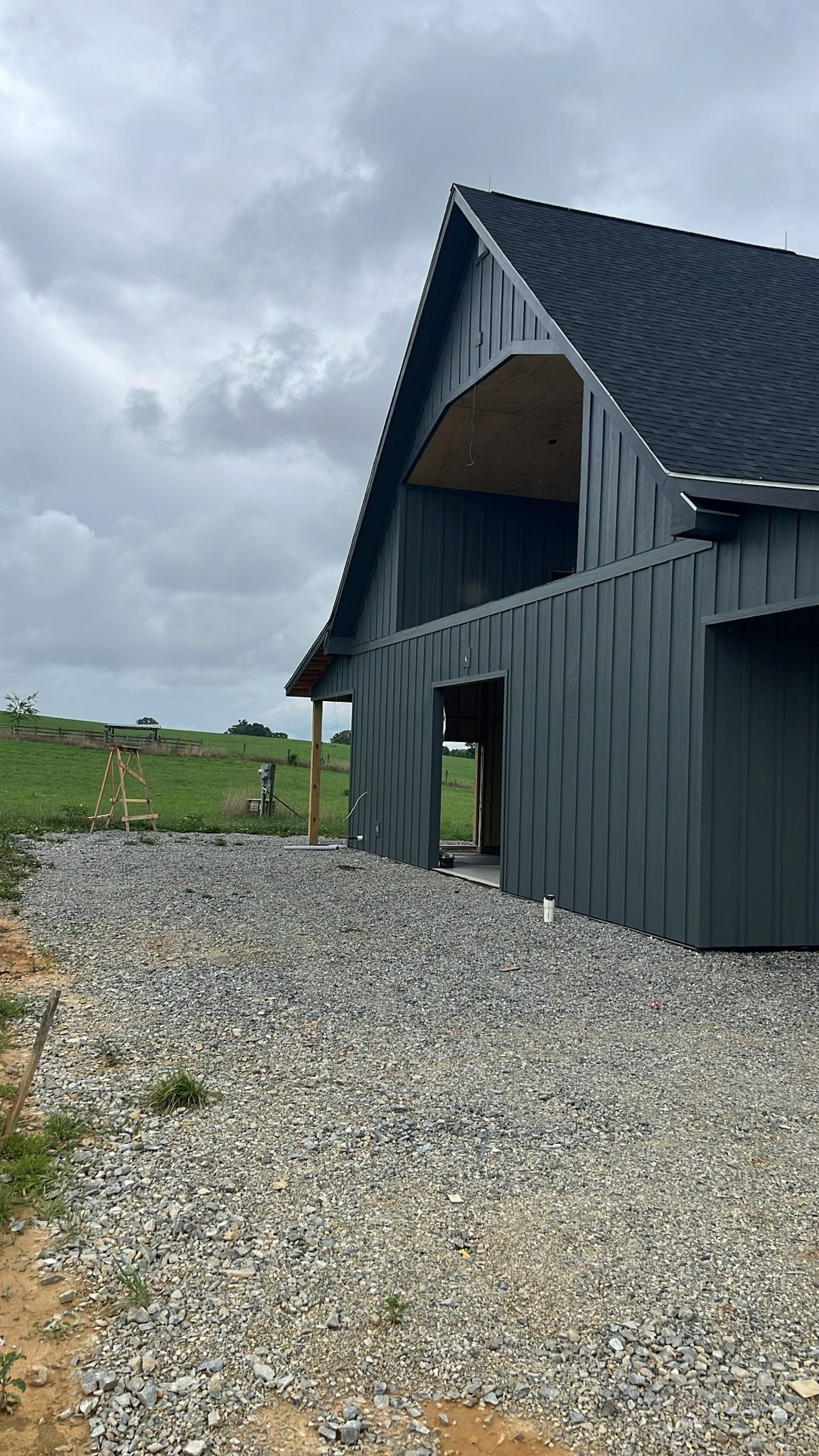 Gray barn-style building with gravel path under overcast sky.
