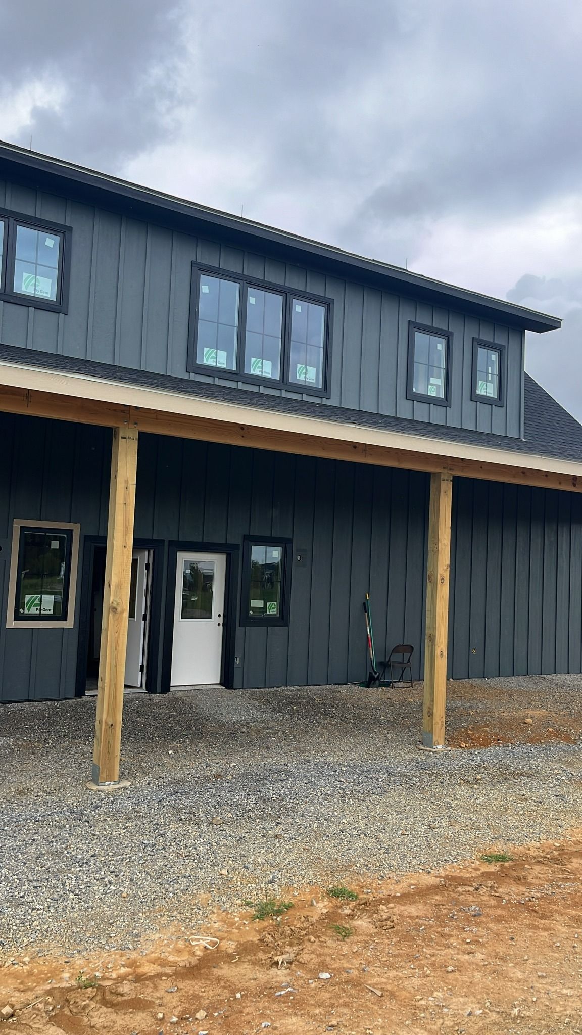 Two-story dark gray building with black-framed windows and a covered porch supported by wooden posts.