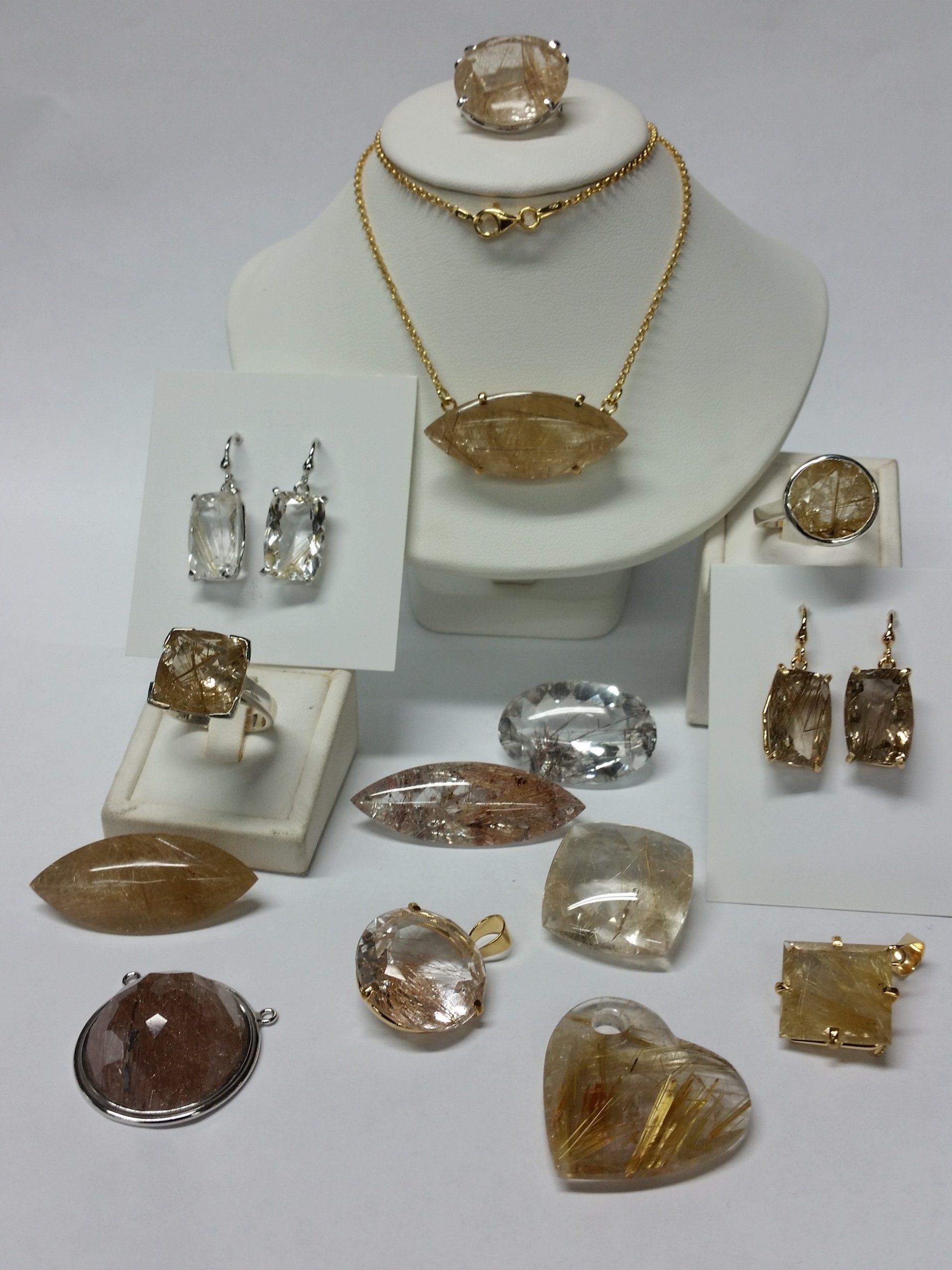 Una mostra di vari gioielli con pietre preziose color oro, tra cui collane, anelli, orecchini e pietre sfaccettate singole.