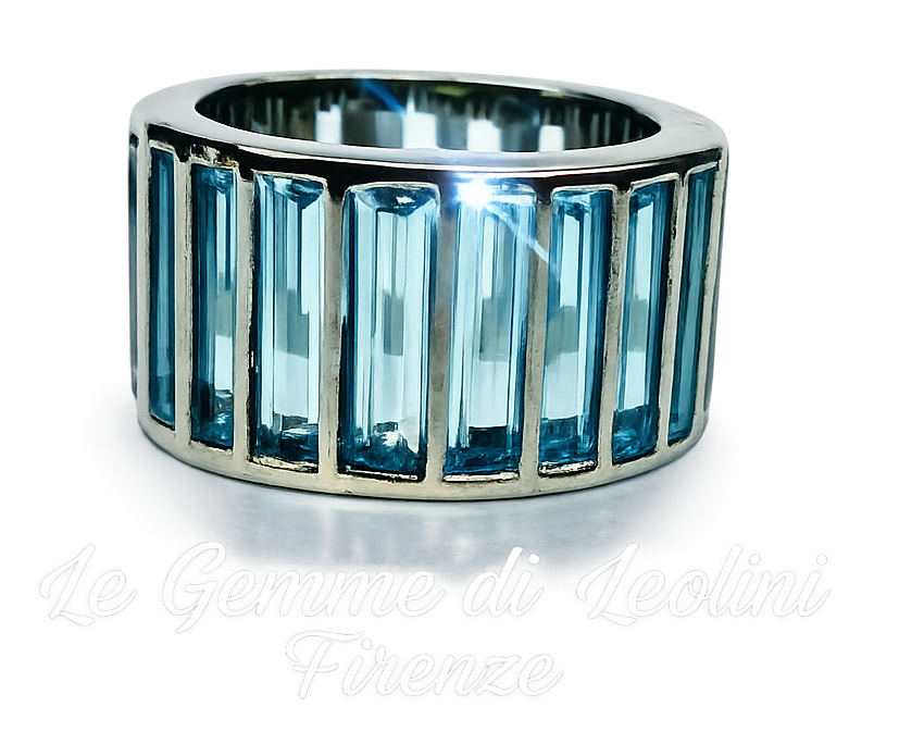 Un ampio anello in argento con una fila di gemme azzurre a taglio baguette incastonate verticalmente.