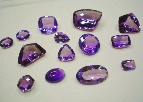 Pietre viola di diverse forme e dimensioni su una superficie bianca