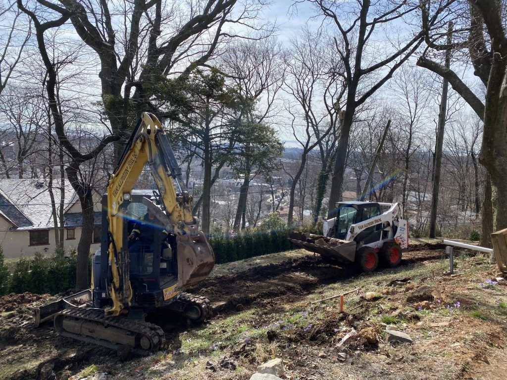 A bulldozer is digging a hole in the ground in the woods.
