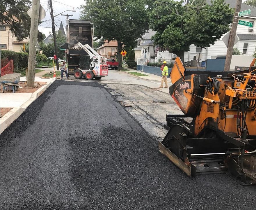 A tractor is laying asphalt on a street