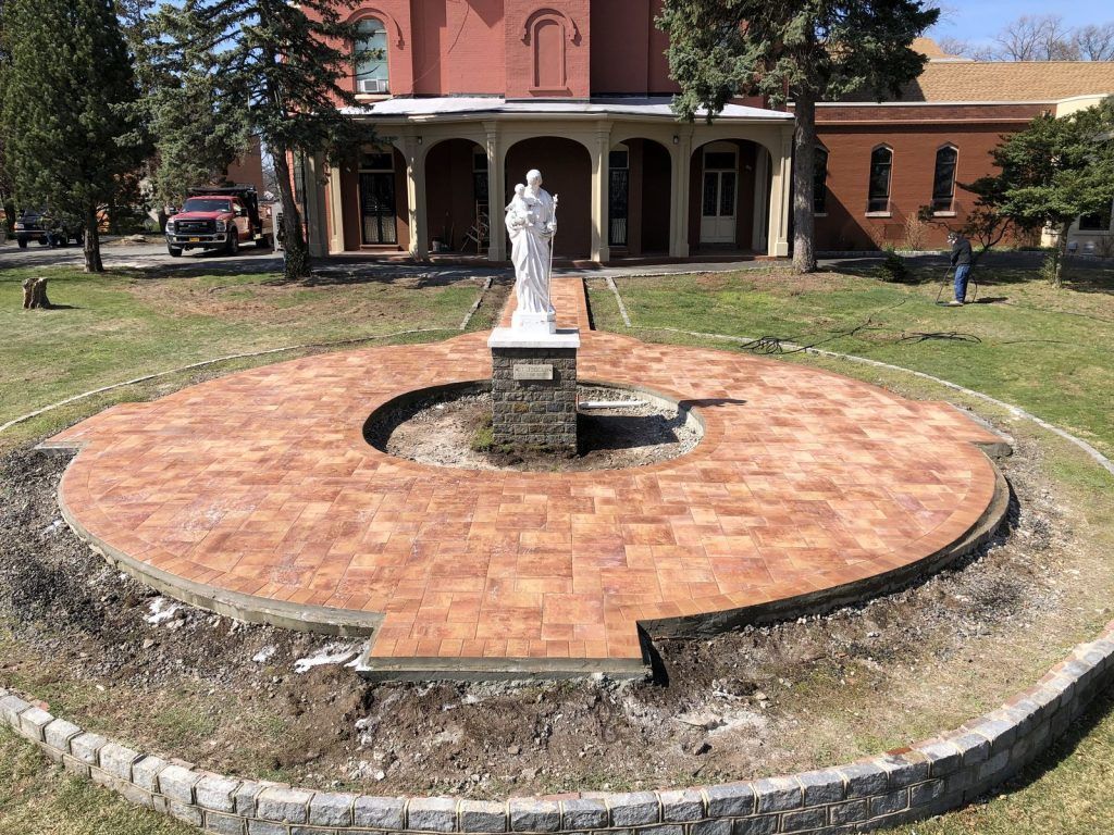 There is a statue of jesus in the middle of a circle in front of a building.