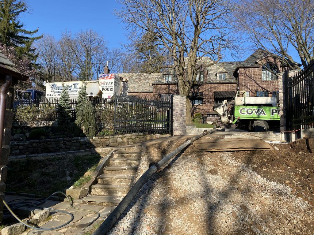 A green truck is parked in front of a brick house.