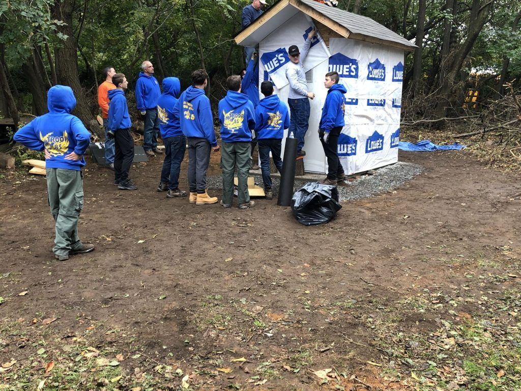 A group of children are standing in front of a shed.