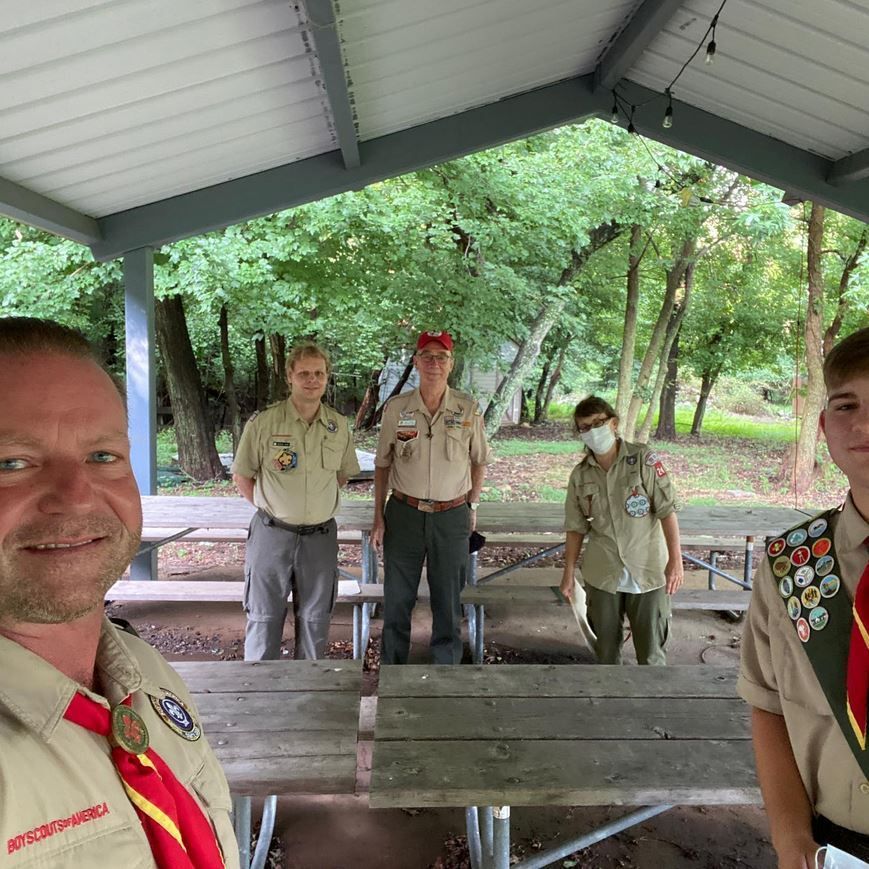 A group of boy scouts are posing for a picture under a pavilion.