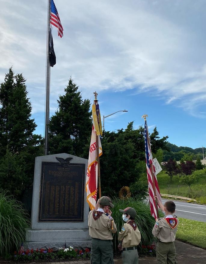 A group of boy scouts standing in front of a flag pole
