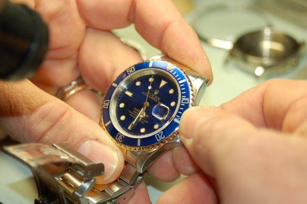 Una persona sta lavorando su un orologio con il quadrante blu