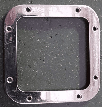 Un quadrato di metallo con dei buchi è su una superficie nera