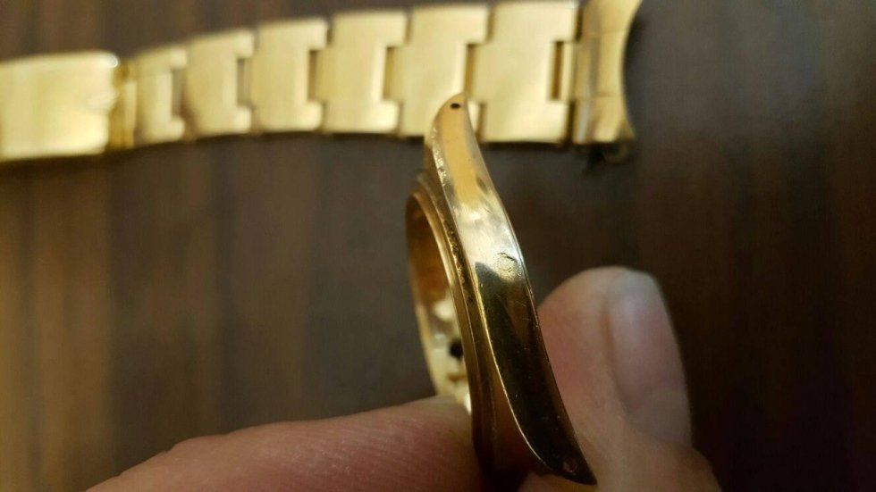 Una persona tiene in mano un cinturino d'oro.