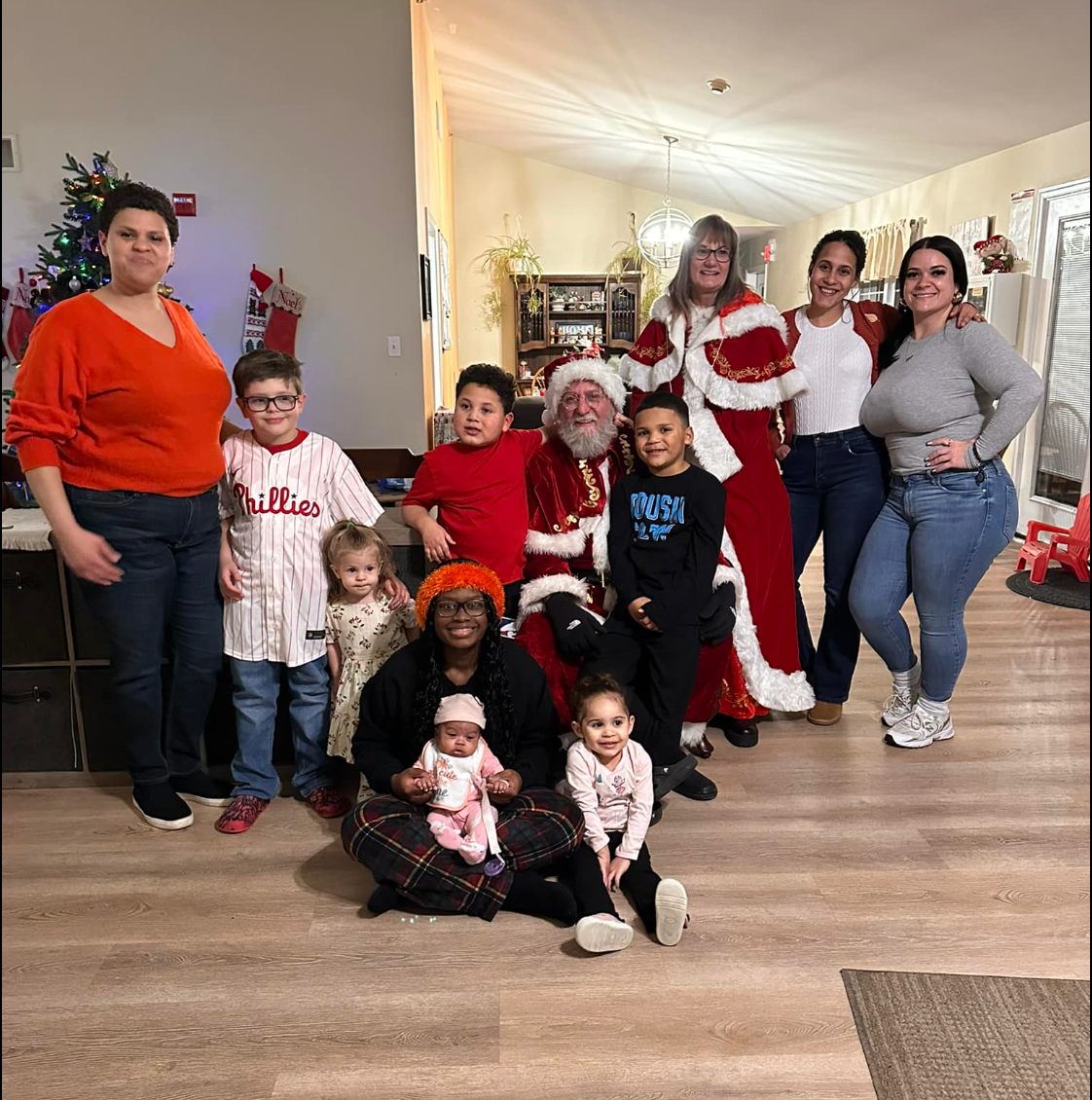 Group of people posing with Santa indoors near a Christmas tree.