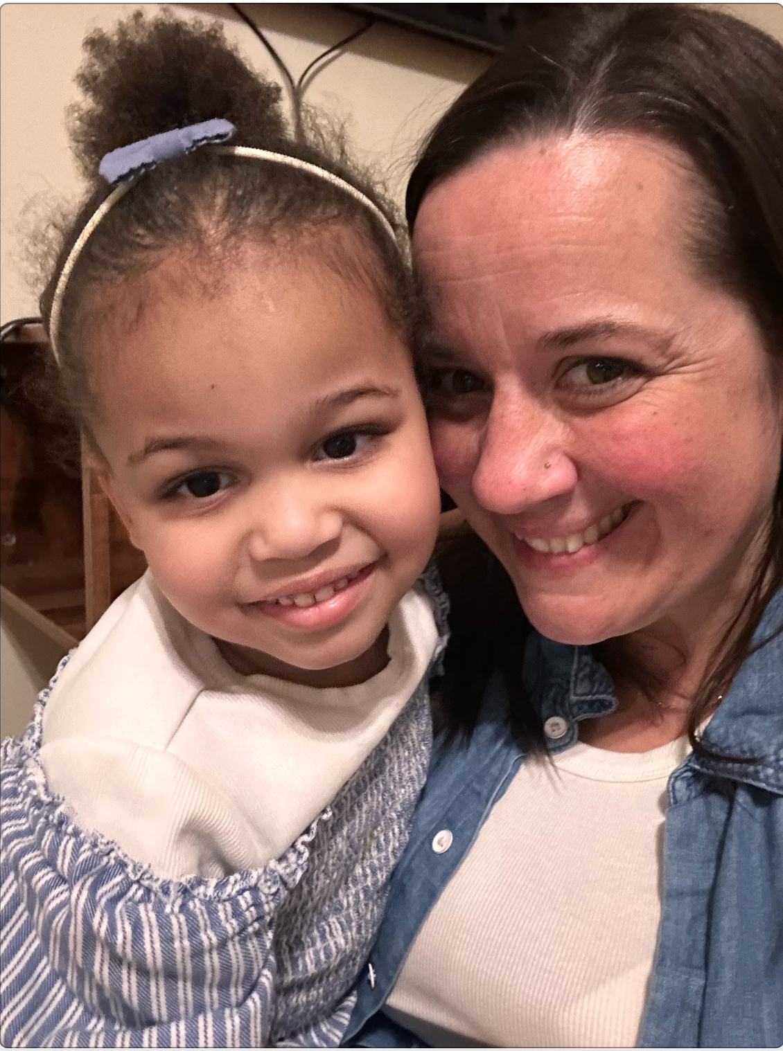 Woman and young child smiling at the camera. Child's wearing a blue headband.