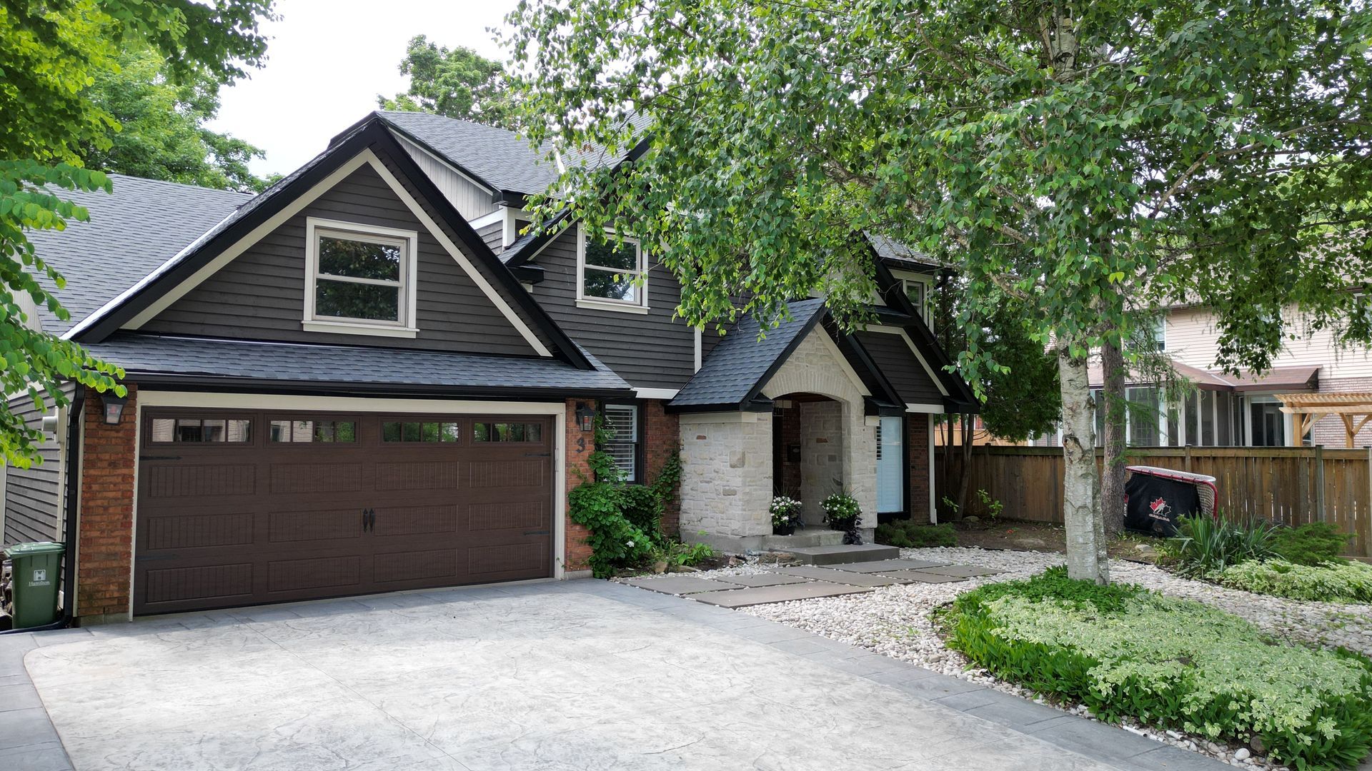 A house with a brown garage door is surrounded by trees