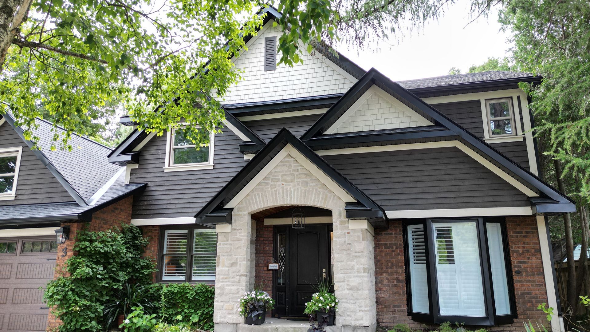 A brick house with a black roof and white trim
