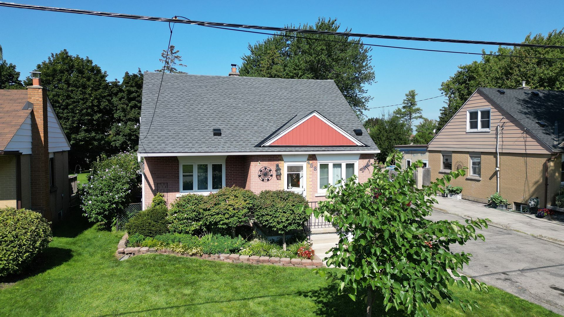 A brick house with a red roof is surrounded by other houses
