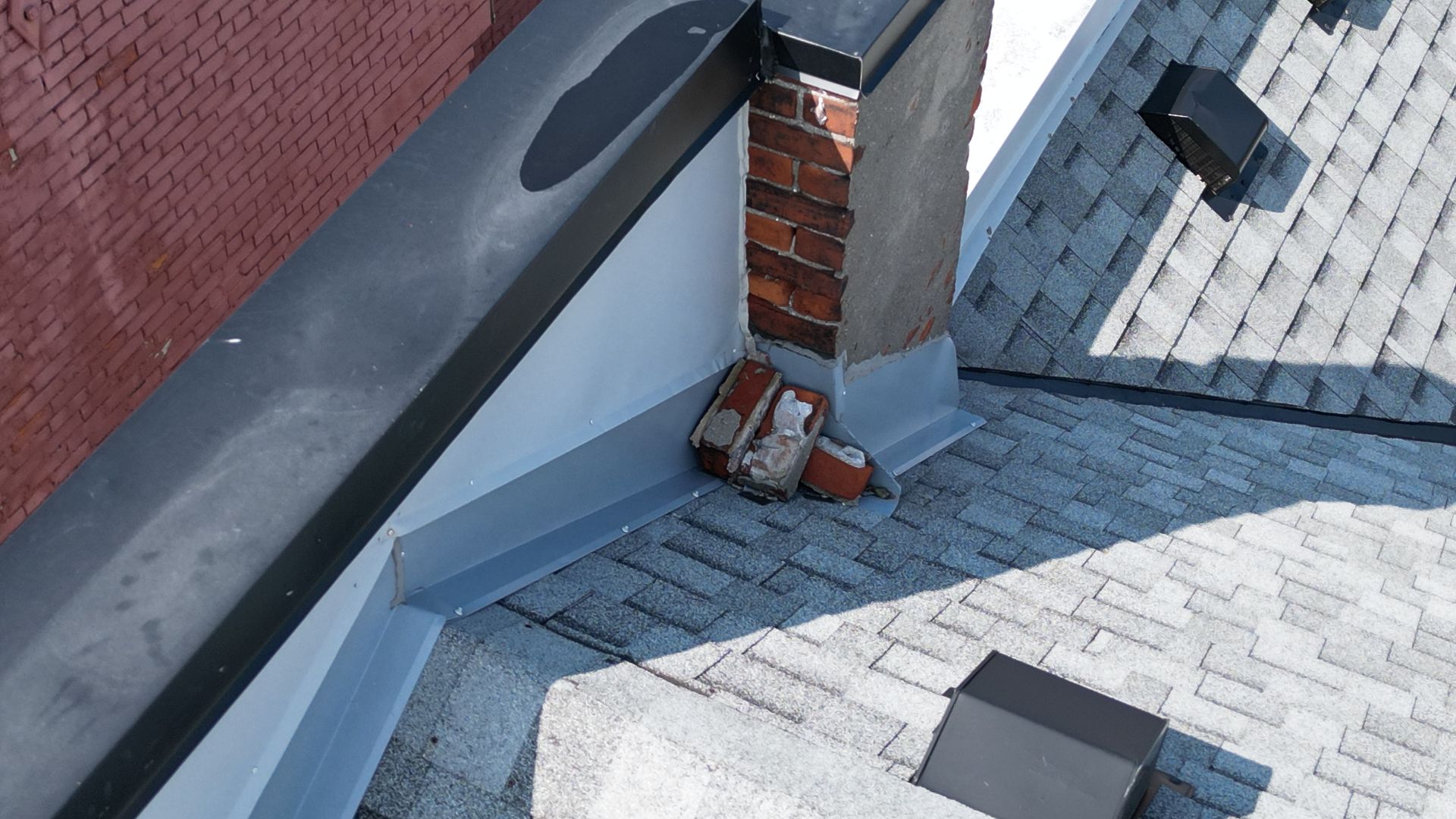 A roof with a chimney on it and a brick wall