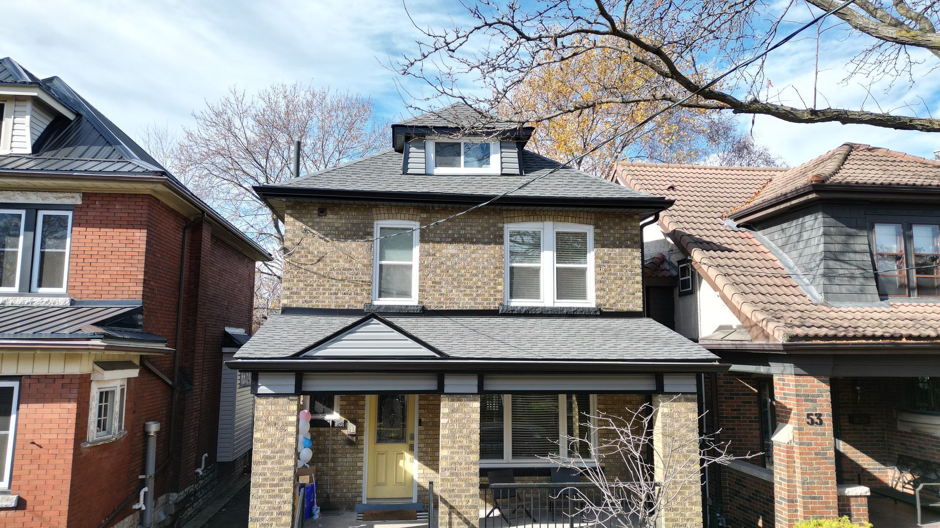A brick house with a gray roof and a yellow door