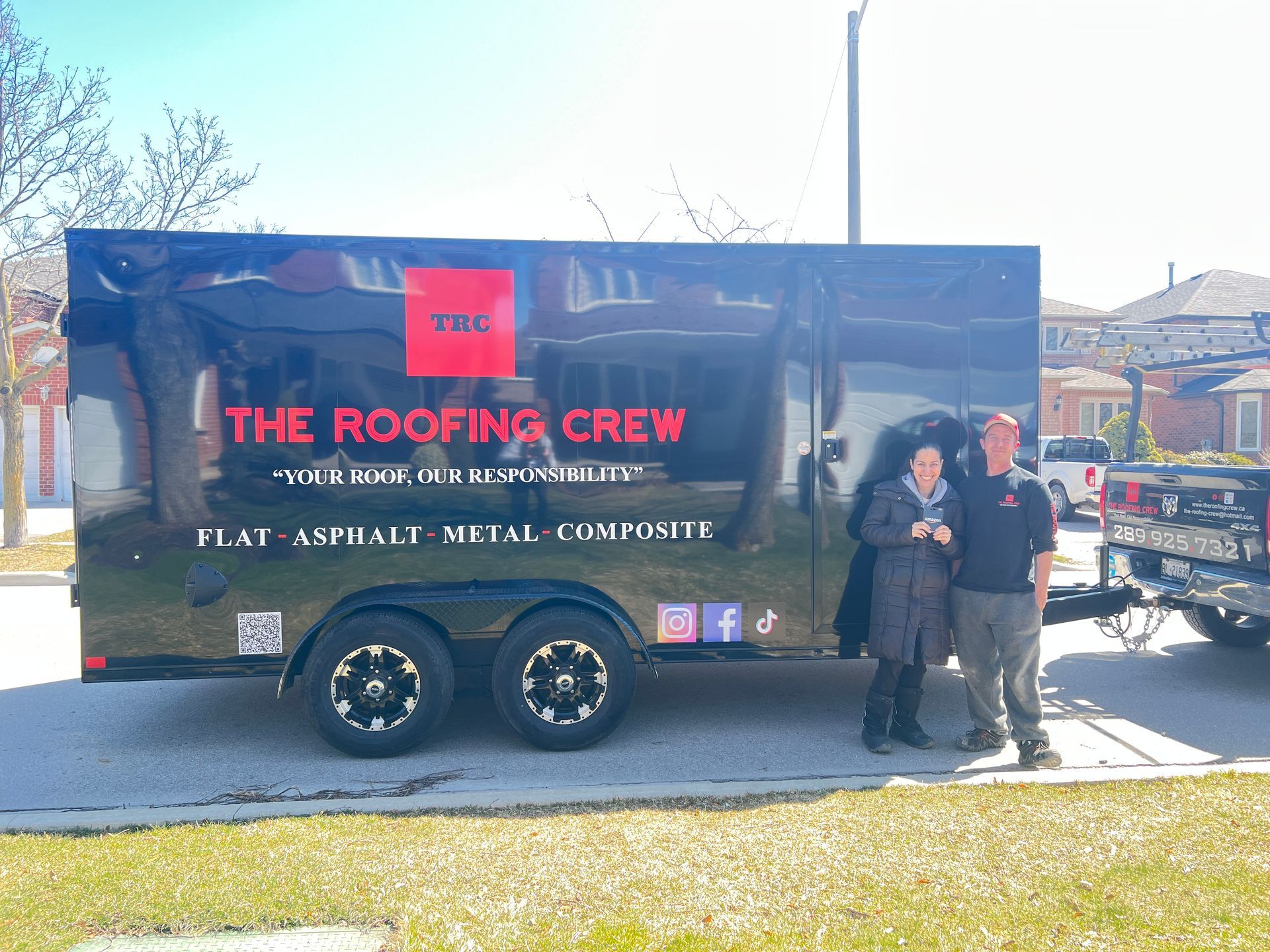 Two people standing in front of a trailer that says the roofing crew