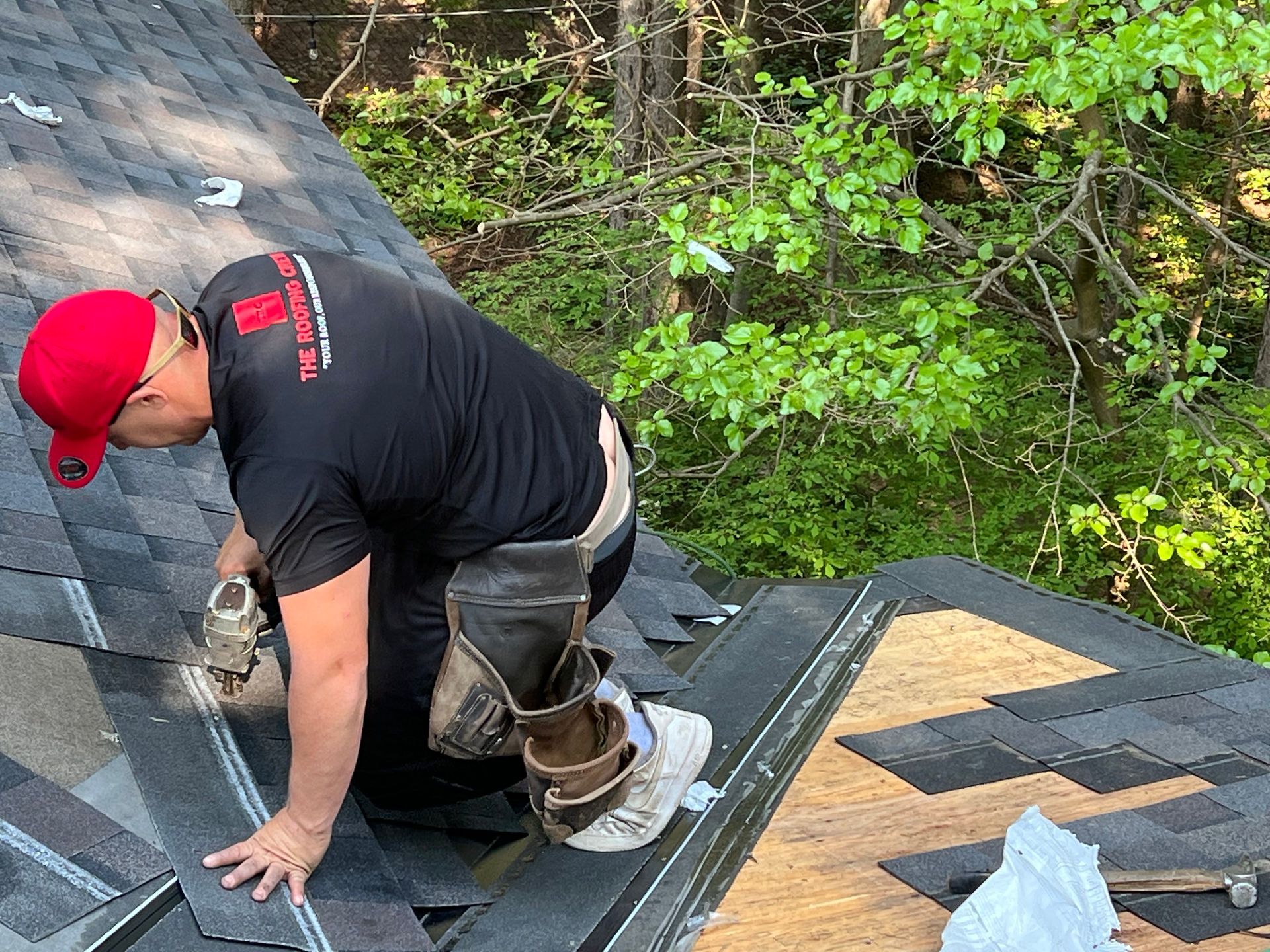 A man wearing a red hat is working on a roof