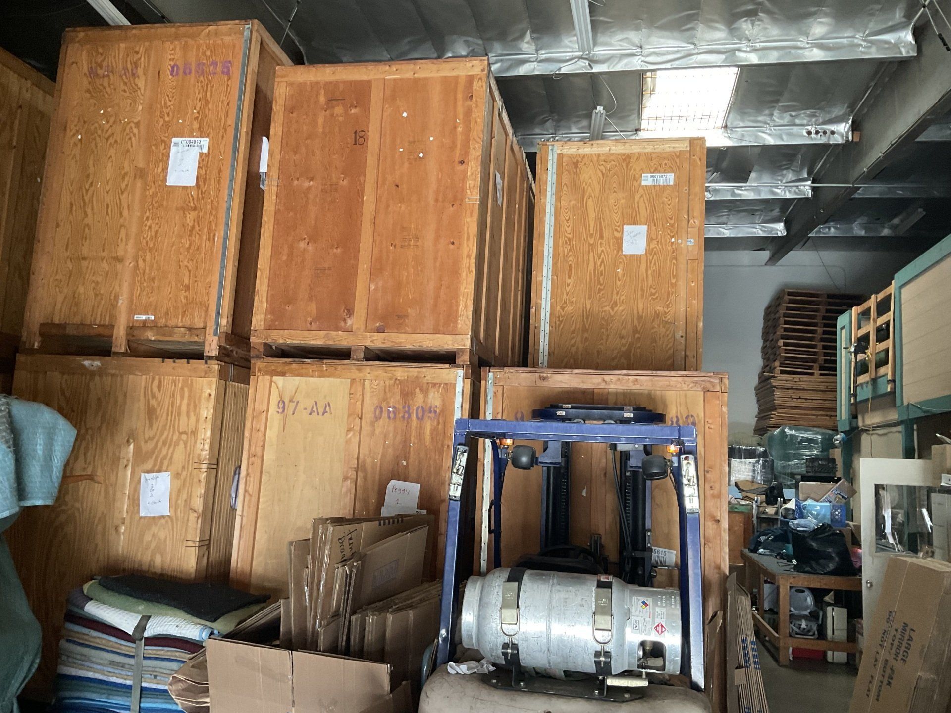 A forklift is driving through a warehouse filled with wooden crates.