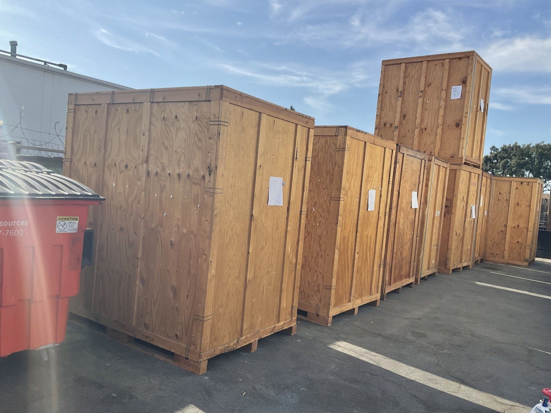 A row of wooden crates are lined up in a parking lot.