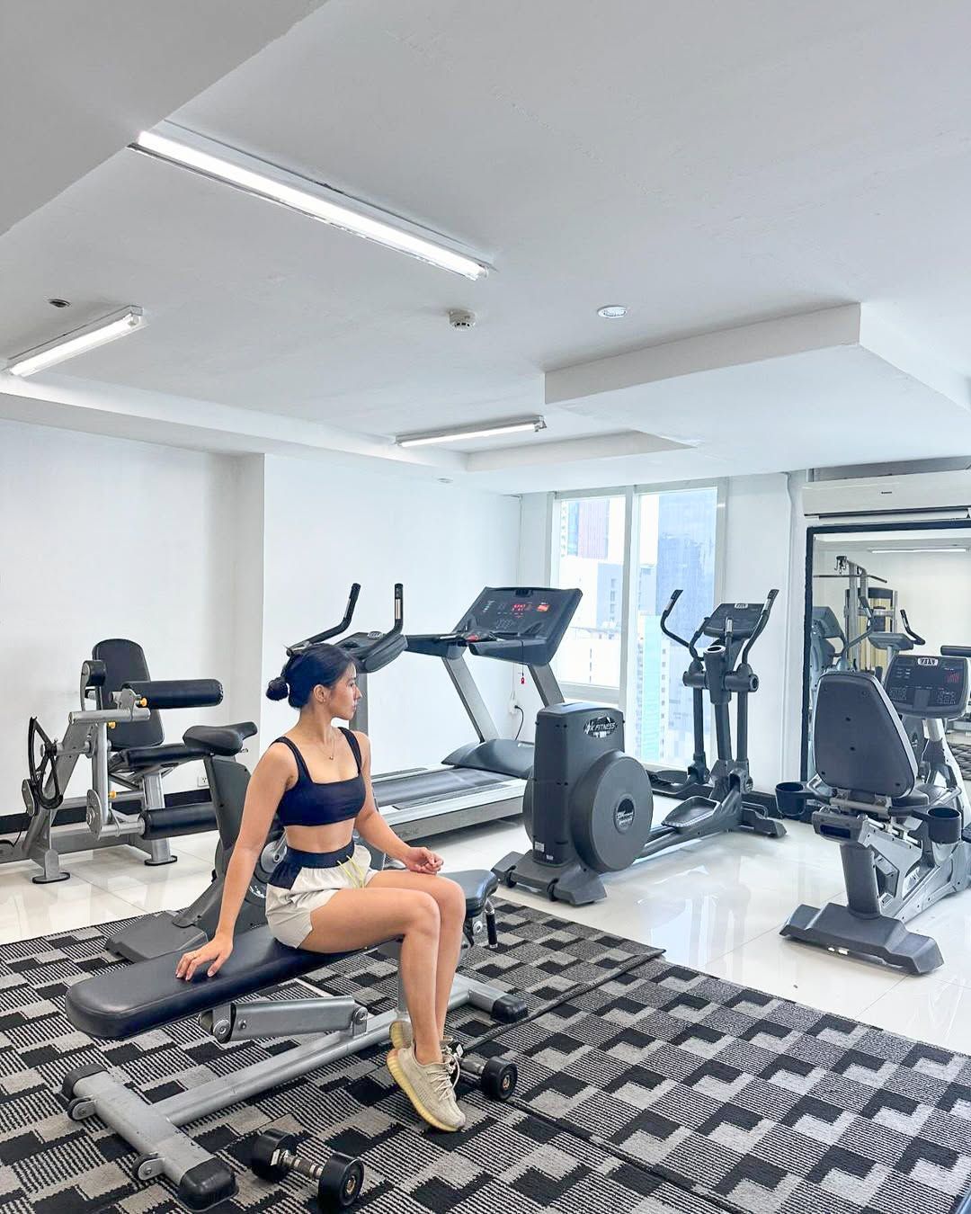 A woman is sitting on a bench in a gym at an affordable hotel in makati