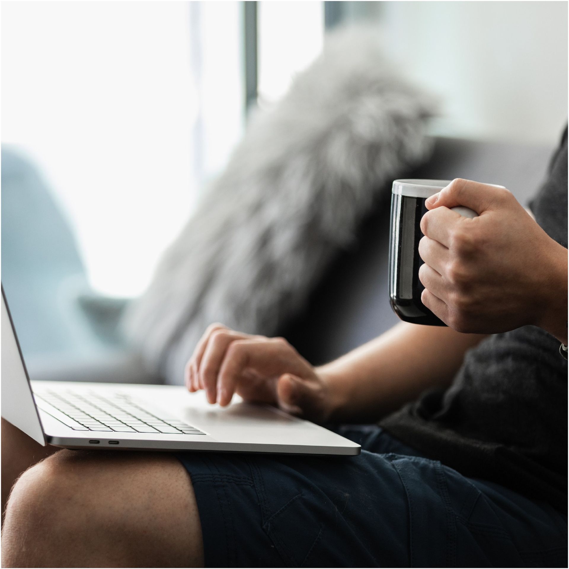 A person is typing on a laptop while holding a cup of coffee at Y2 Residence Hotel.