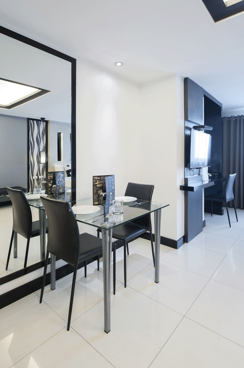 A dining room with a table and chairs and a large mirror found in Studio Deluxe Room