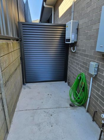 A Green Hose is Hanging on a Wall Next to a Side Gate —  SCF Industries Pty Ltd in Albion Park Rail, NSW