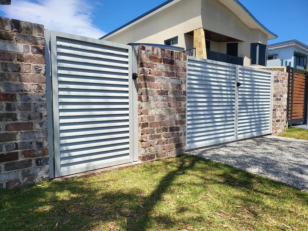 A White Gate is Sitting Next to a Brick Wall in Front of a House —  SCF Industries Pty Ltd in Shellharbour, NSW