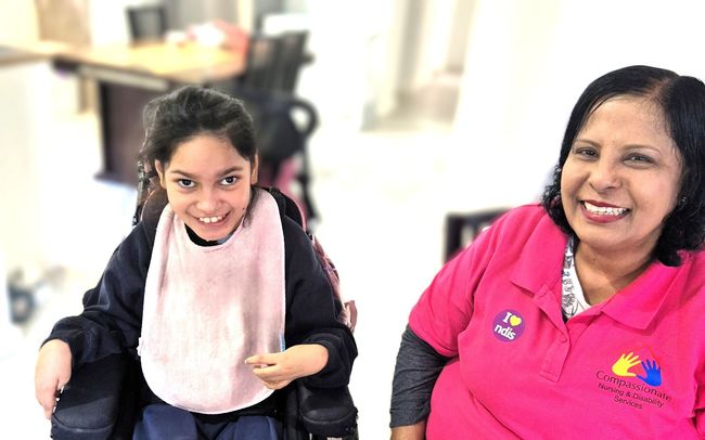 disabled child in a wheelchair with a care assistant