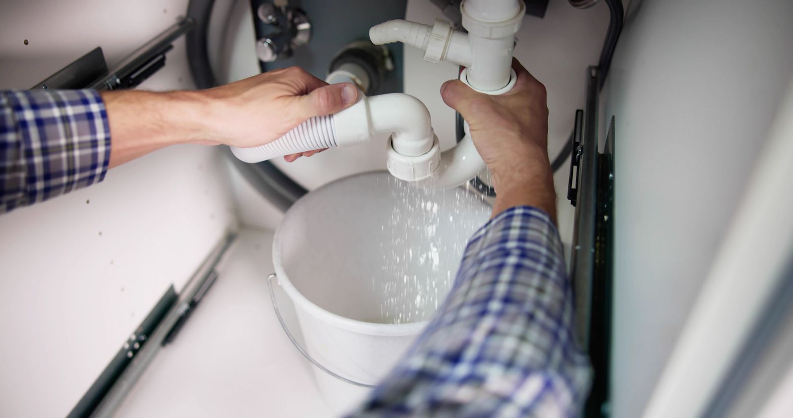 A plumber is fixing a water heater in a bathroom.