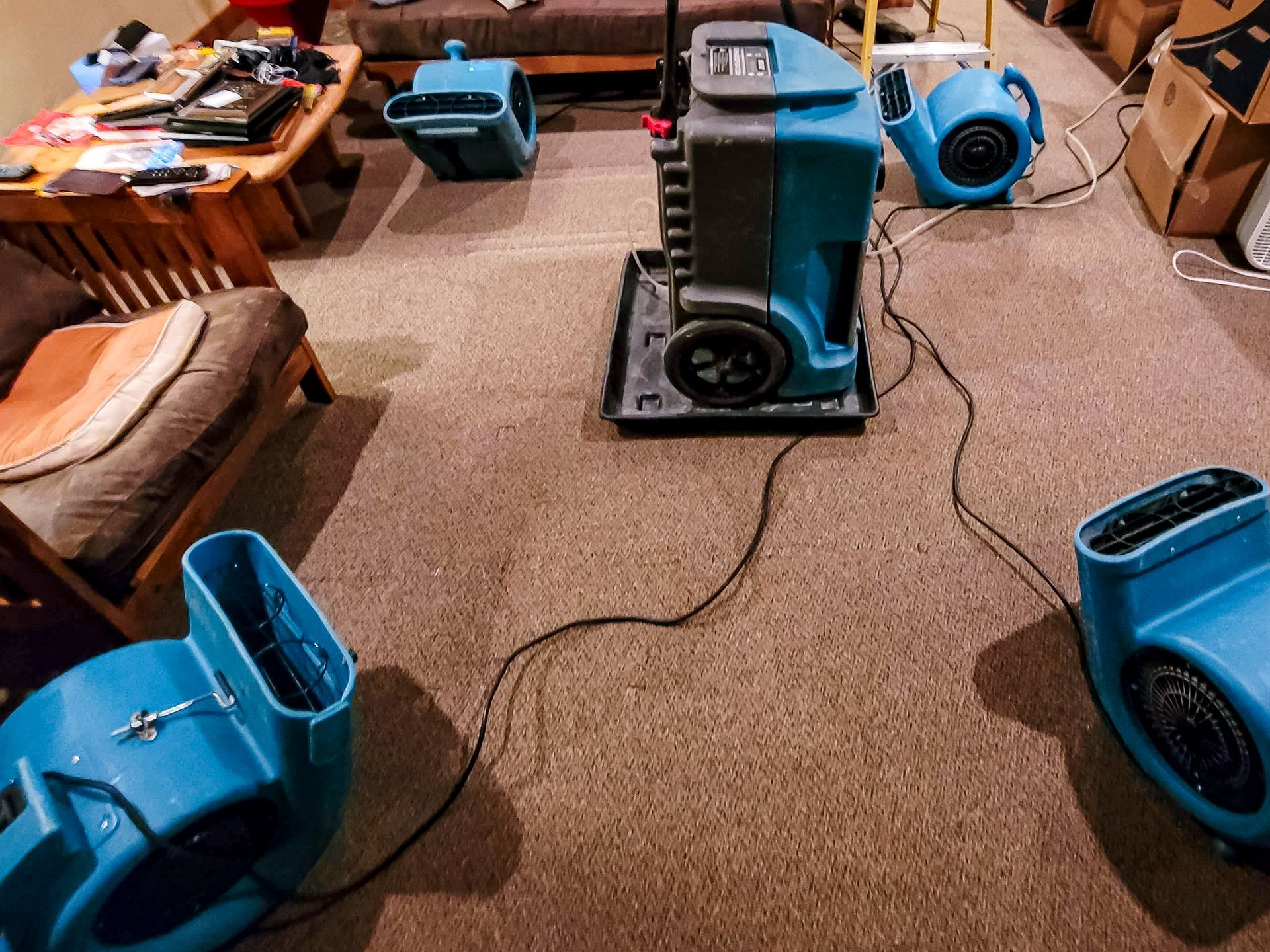 A residential room undergoing water damage restoration with air movers and a dehumidifier.