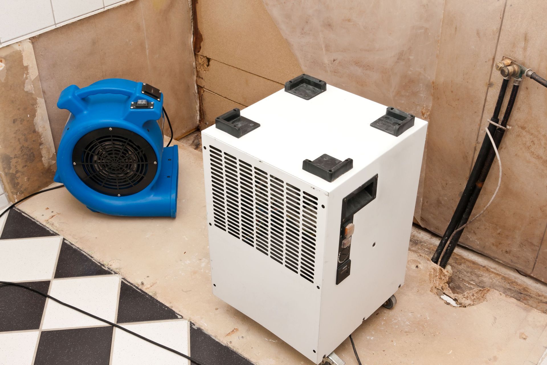 Restoration equipment is placed on the tiled floor to dry the water-damaged room. Restoration equipment is placed on the tiled floor to dry the water-damaged room.