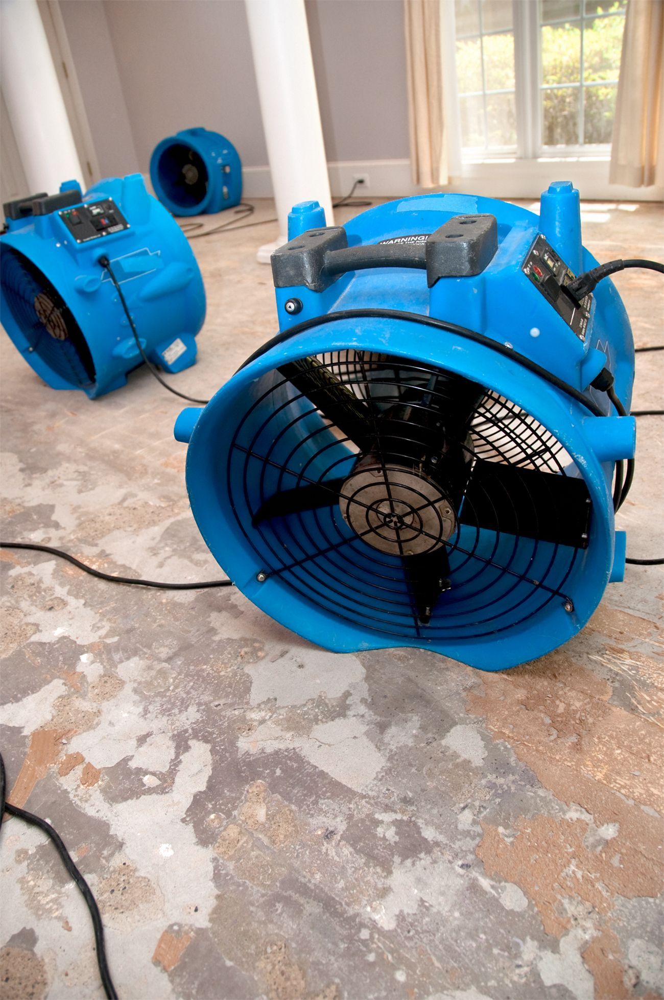 Industrial fans and dehumidifiers placed in flooded room for water damage restoration services.