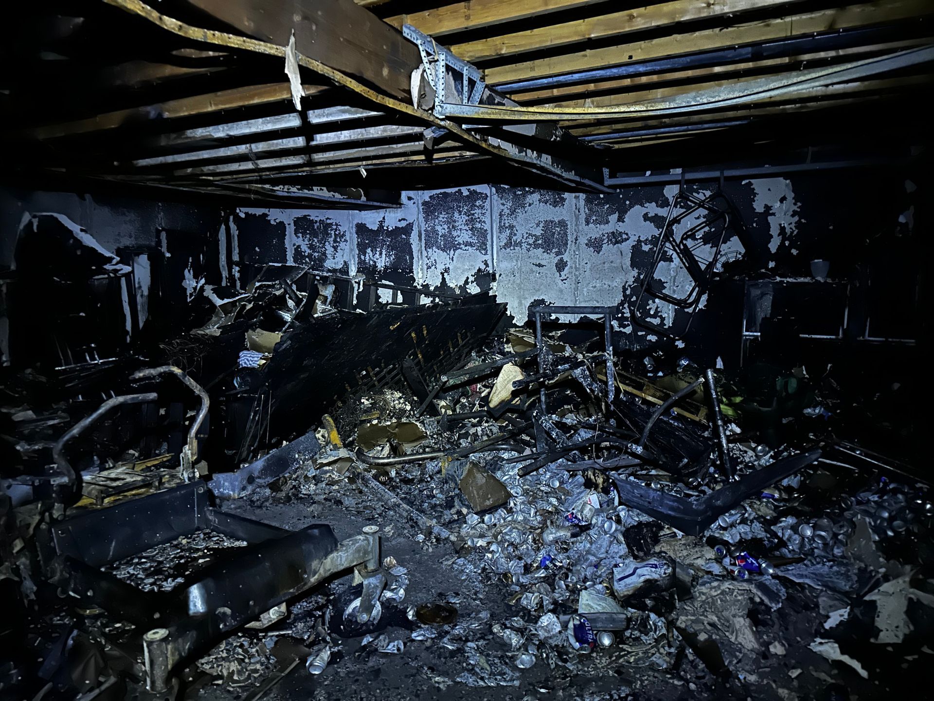 Interior view of a fire-damaged room, charred debris and structural damage visible.
