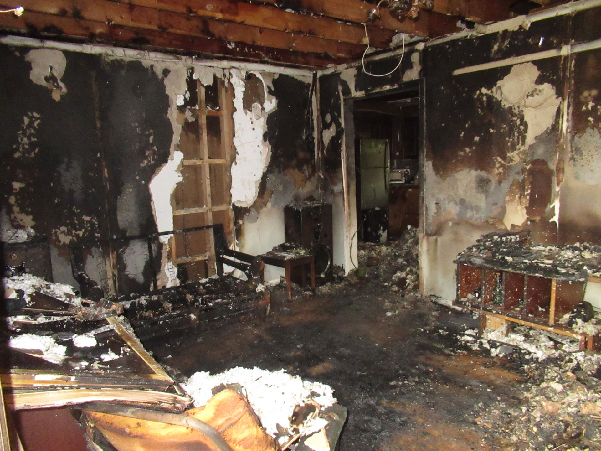 Interior room damaged by fire; walls and ceiling charred, furniture destroyed.