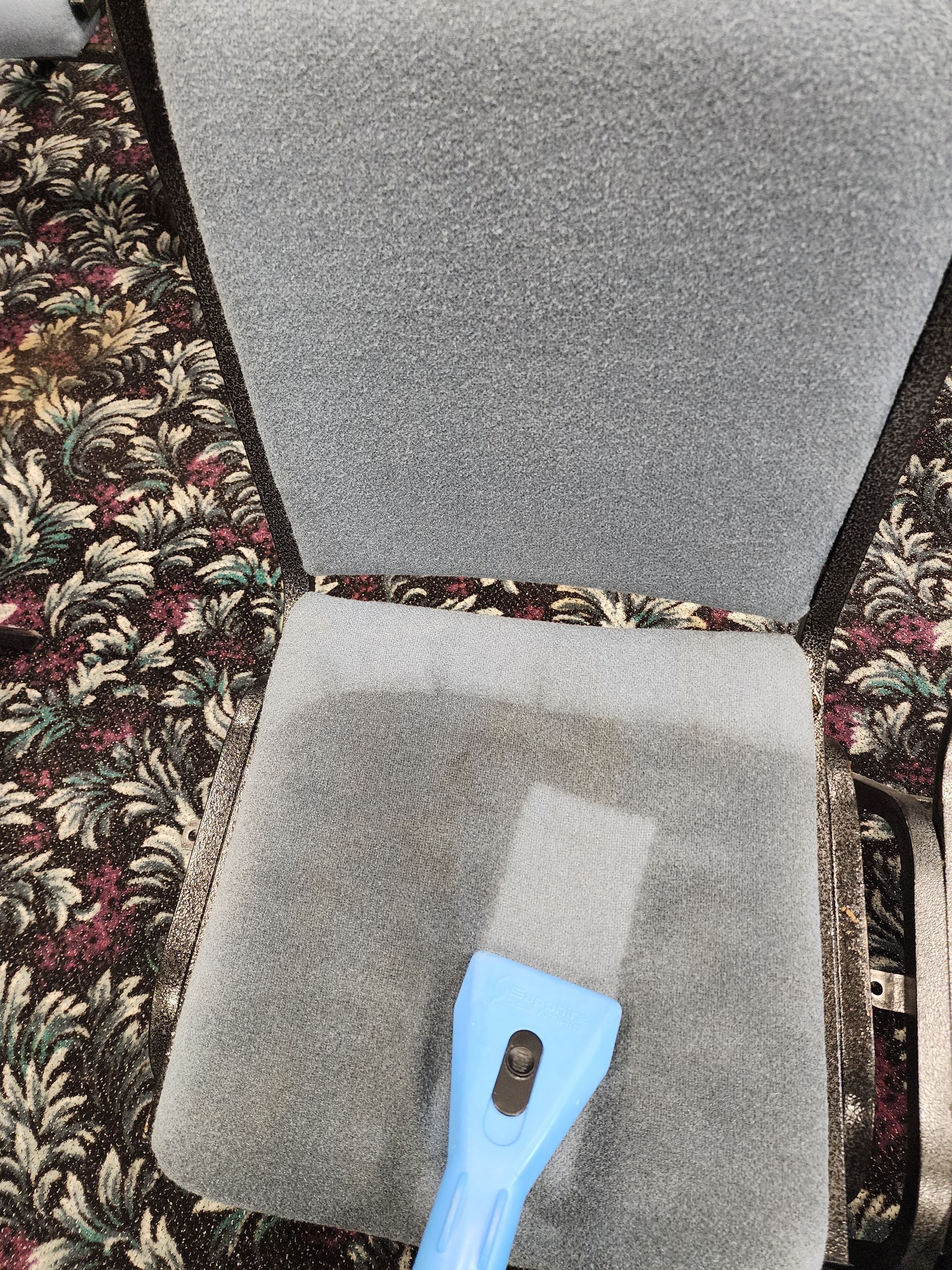 A blue vacuum cleaner is sitting on top of a carpeted chair.