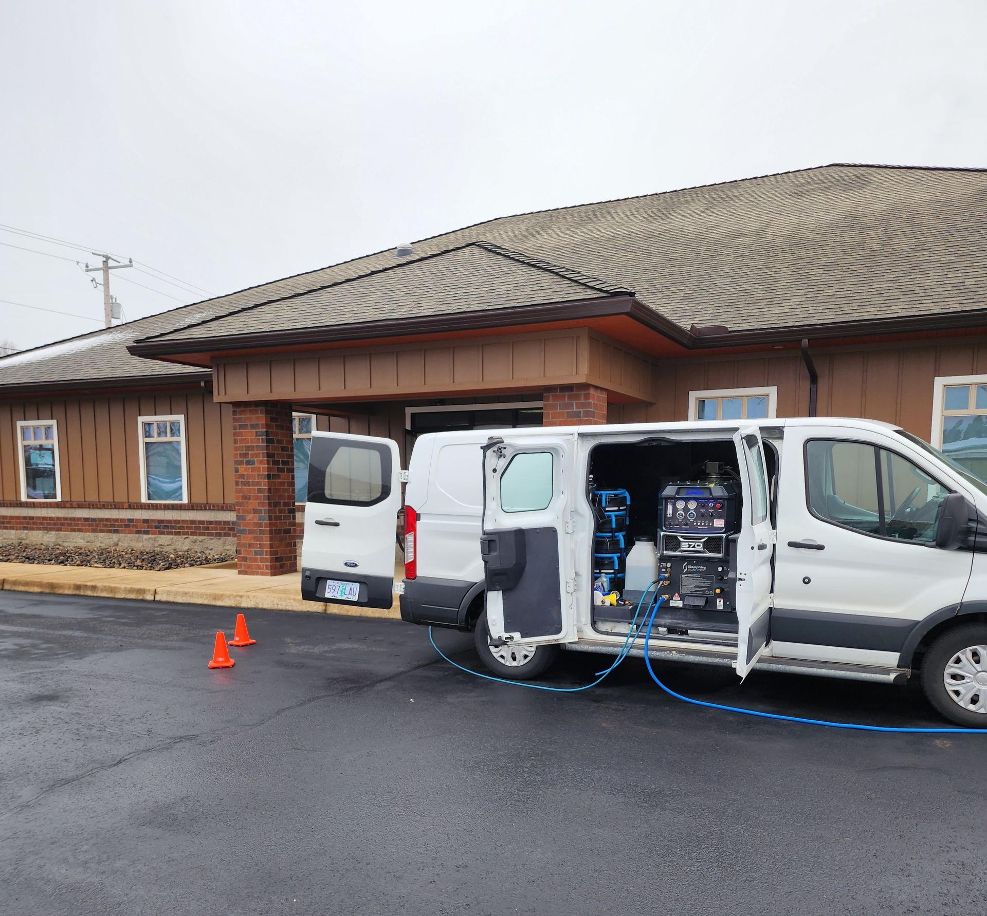 A white van is parked in front of a brown building