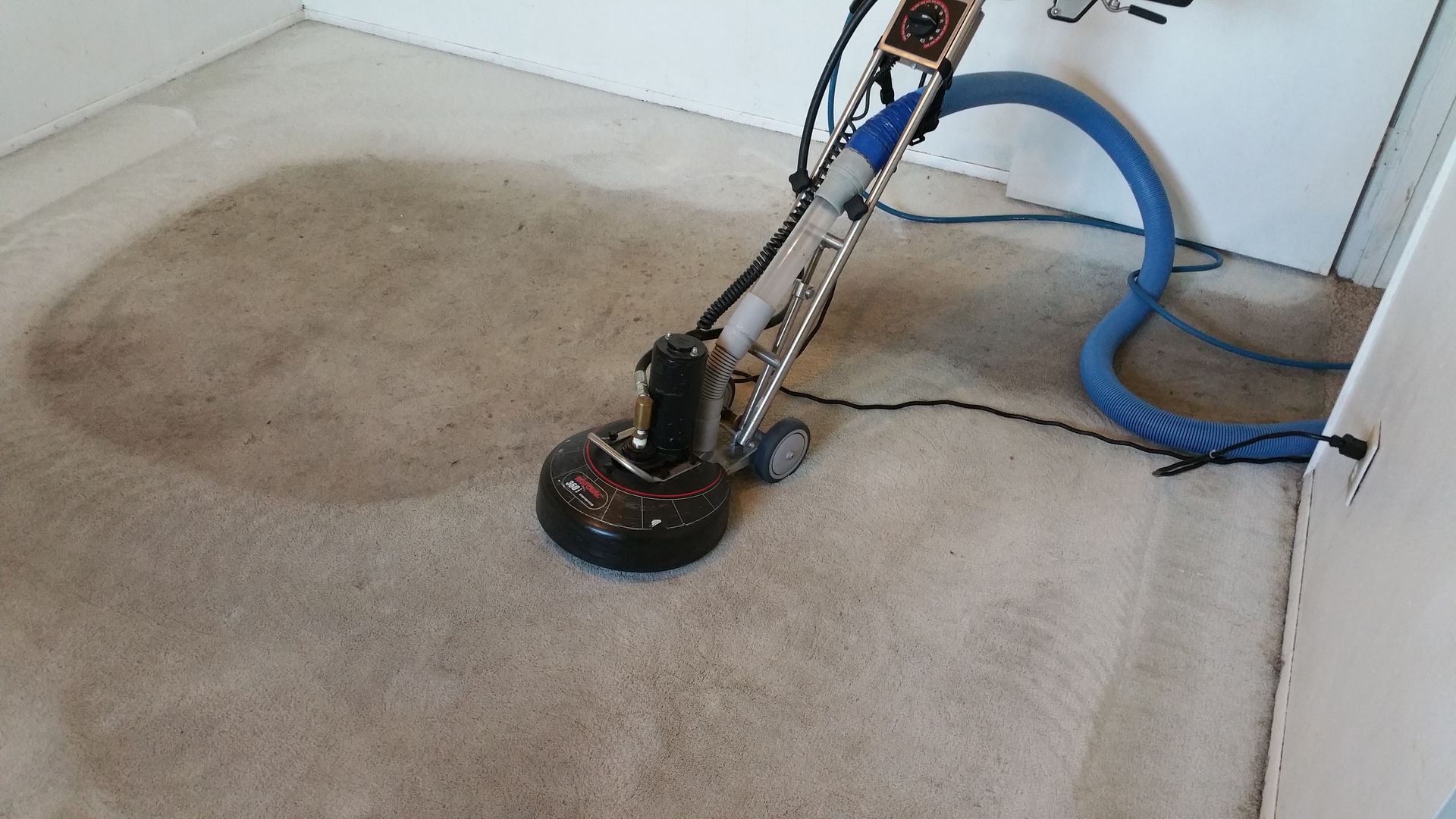 A vacuum cleaner is cleaning a carpet in a room.