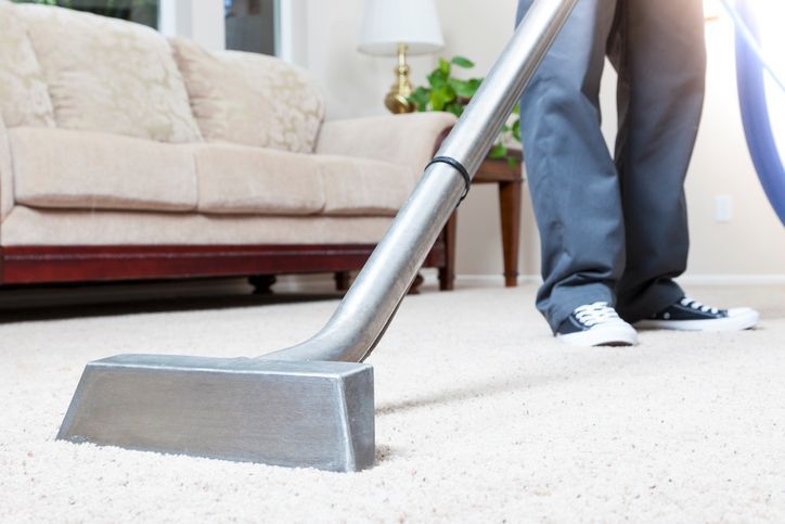 A person is using a vacuum cleaner to clean a carpet in a living room.