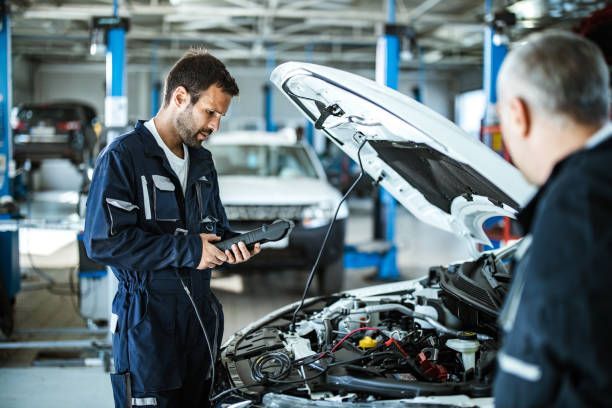 Two mechanics inspecting car engine bay