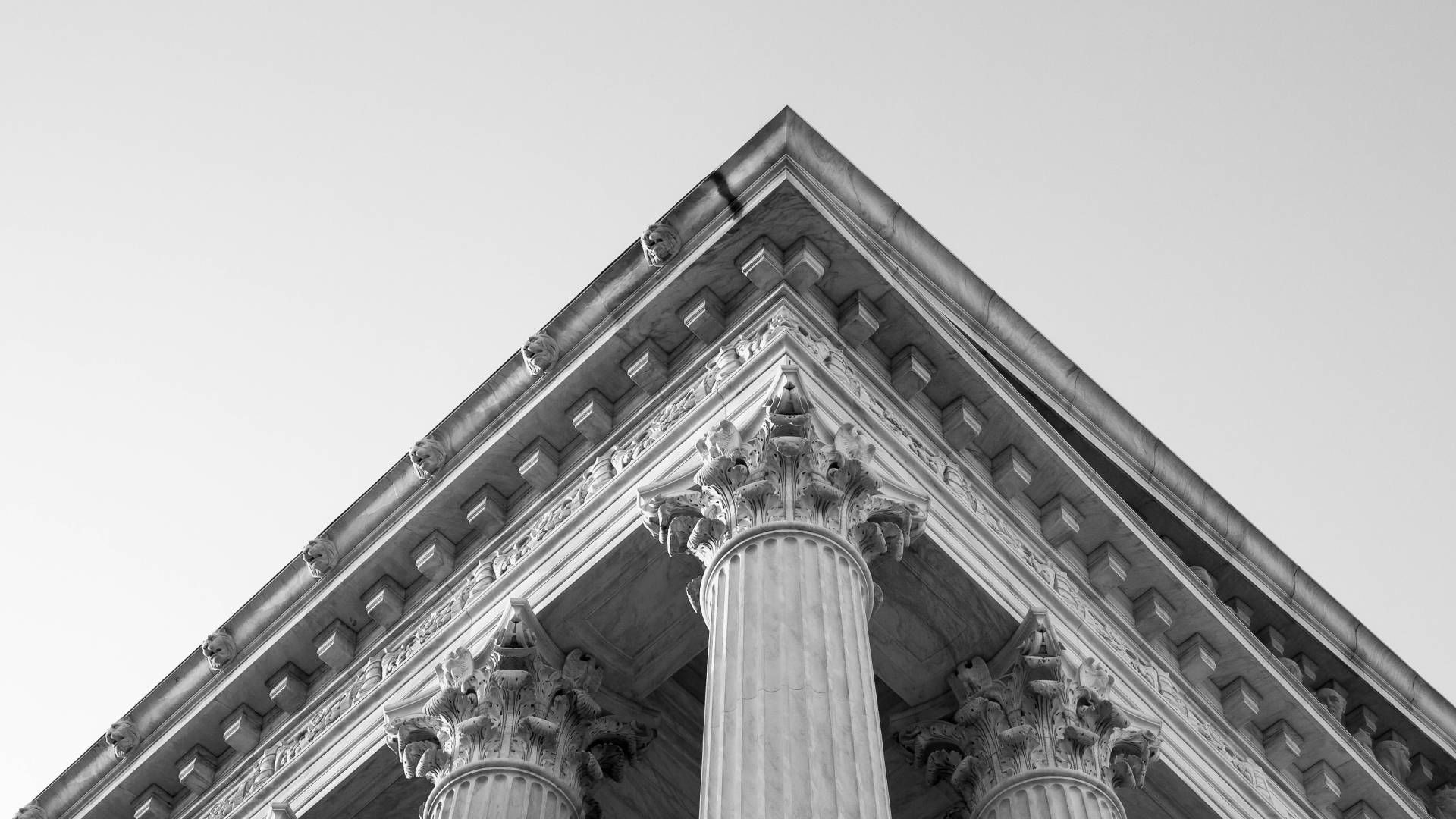 A black and white photo of the corner of a building with columns.