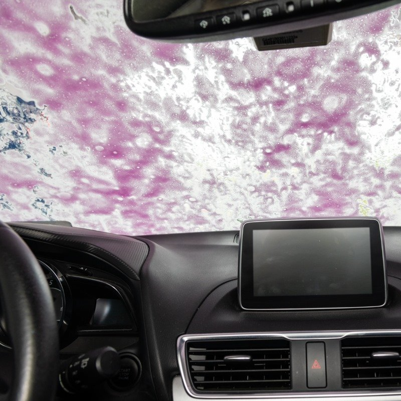 Pink suds on the window of a car in the car wash.
