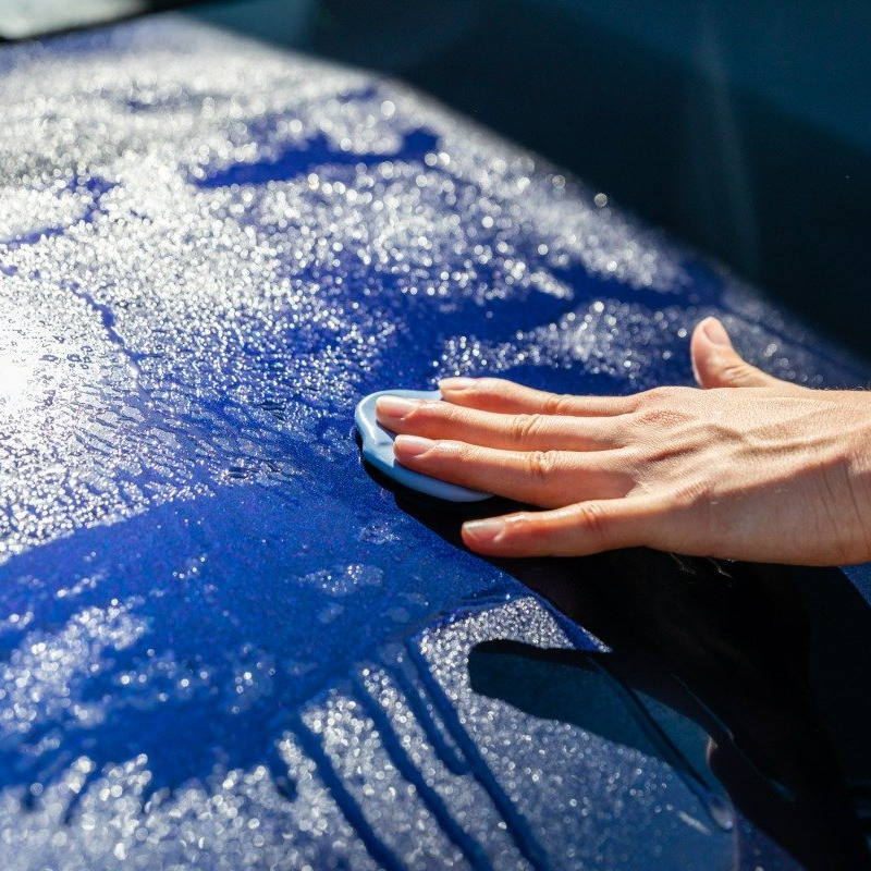 hand washing exterior of blue vehicle.