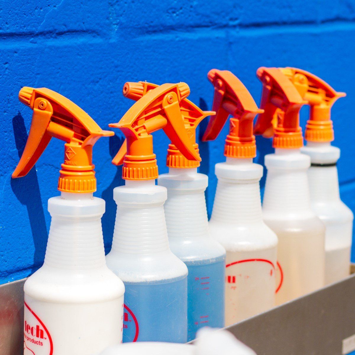 Car Wash Detailing - cleaning spray bottles lined up against blue wall