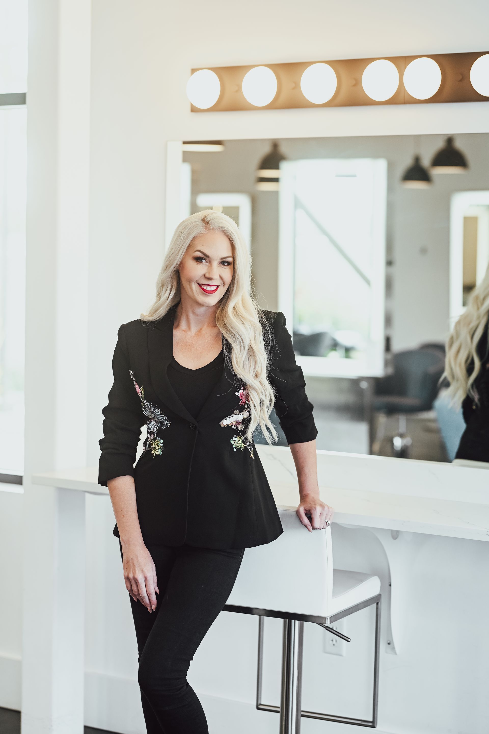 AnneMarie Krainich, owner of Ottalaus Salon, is standing in a room with her arms crossed and smiling.